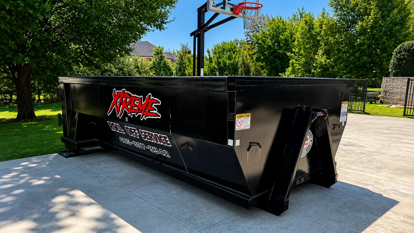 Black Xtreme dumpster positioned at an angle in a residential driveway